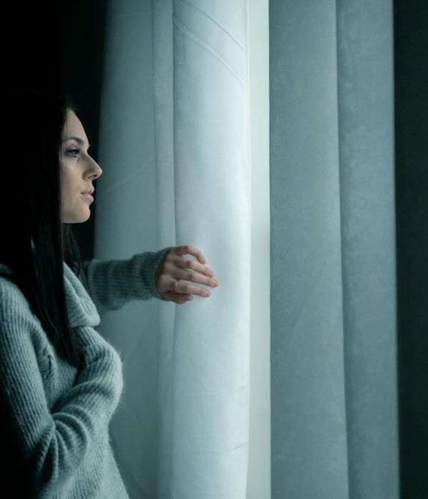 Woman in a calm, focused pose in a dark room with ruby accents.